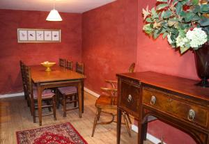 ein Esszimmer mit einem Tisch und einer Blumenvase an der Wand in der Unterkunft Bittles Cottage in Dorchester