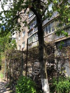 a building with a fence in front of a tree at Demeevsky Hostel in Kyiv