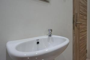 lavabo blanco con grifo en el baño en RedDoorz Syariah near Alun Alun Kebumen, en Kebumen
