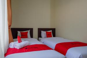 two beds in a room with red and white pillows at RedDoorz Syariah near Alun Alun Kebumen in Kebumen
