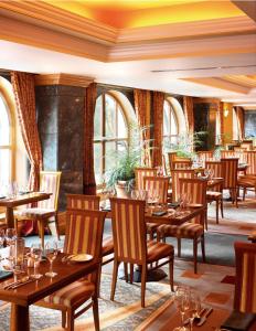 基拉尼的住宿－基拉尼廣場溫泉酒店，餐厅设有木桌、椅子和窗户。