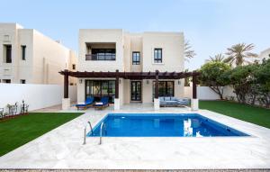 a villa with a swimming pool in front of a house at Dubai Creek Club Villas in Dubai