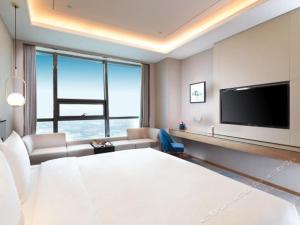 a hotel room with a large bed and a tv at Auto City Ruili Hotel in Jiading