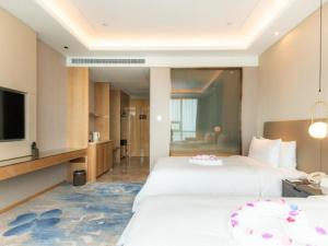 a hotel room with two beds and a television at Auto City Ruili Hotel in Jiading