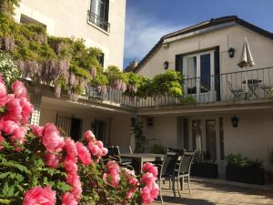 a house with a table and chairs and pink flowers at Les gîtes du Clos Saint-Martin in Maule