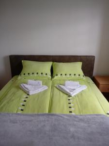 un letto con lenzuola verdi e due asciugamani sopra di Apartments Vila Velickovic a Zlatibor