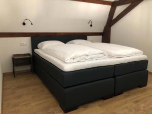 a bed with white sheets on it in a room at B&B De Hoffstal in Sassenheim