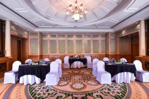 a ballroom with tables and white chairs and a chandelier at Al Ain Rotana in Al Ain