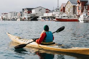 a person is sitting in a kayak in the water at Villa Bryggekanten - by Classic Norway Hotels in Henningsvær
