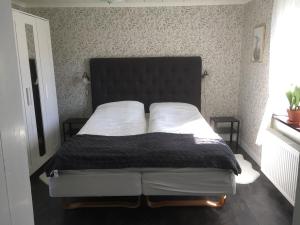a bed with a black headboard in a bedroom at Stenbrottets lillstuga in Falköping
