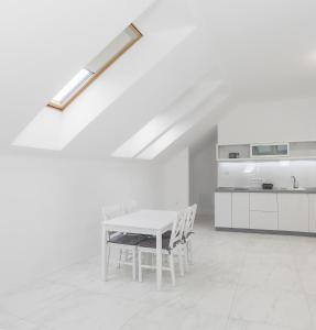 a white kitchen with a white table and chairs at Corso Lux Apartman in Gyula