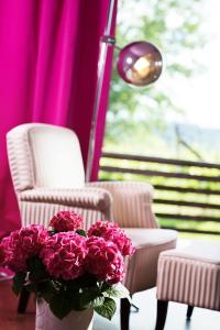 un jarrón de flores rosas en una mesa junto a una silla en Weingartenhotel Harkamp Südsteiermark en Sankt Nikolai im Sausal