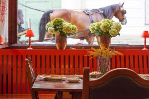 een tafel met twee vazen met bloemen en een paard op de achtergrond bij Hotel Wolf in Salzburg