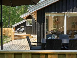 una terraza de madera con sillas, mesas y sombrilla en 8 person holiday home in Nex en Neksø