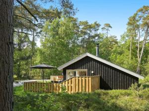 a cabin in the woods with an umbrella at 8 person holiday home in Nex in Neksø