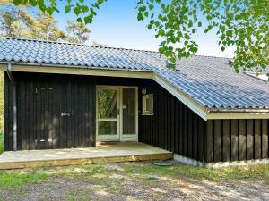 a black house with a porch and a door at 8 person holiday home in Nex in Neksø