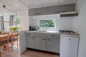 a kitchen with white cabinets and a sink and a table at Luxe chalet op de Veluwe in Ermelo +12 photos