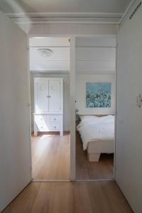 een slaapkamer met een wit bed en een spiegel bij Luxe chalet op de Veluwe in Ermelo