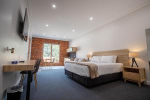 una camera con letto, scrivania e tavolo di Red Waratah Accommodation a Bendigo