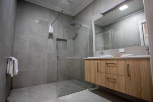 ein Badezimmer mit Dusche, Waschbecken und Spiegel in der Unterkunft Red Waratah Accommodation in Bendigo