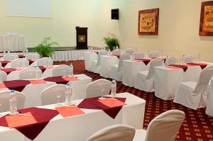 una stanza piena di tavoli e sedie bianchi con tovaglioli rossi di Occidental Cozumel - All Inclusive a Cozumel