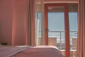 a bedroom with a bed and a sliding glass door at Hotel Nais Beach in Durrës
