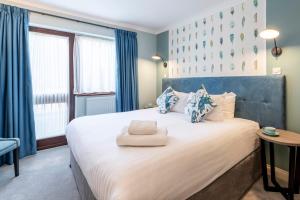 a bedroom with a large white bed with blue curtains at Wisteria Hotel in Oakham
