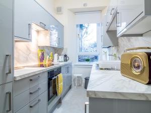 uma cozinha com armários brancos e uma grande janela em Stylish & Charming Retreat for 2- City Centre! em Edimburgo