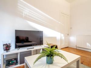 ein Wohnzimmer mit einem TV und einem Tisch in der Unterkunft Stylish & Charming Retreat for 2- City Centre! in Edinburgh
