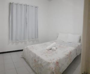 um quarto com uma cama com um cobertor branco e uma janela em CHALÉS ENCANTOS DA ILHA em Barra dos Coqueiros