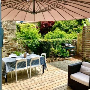 een tafel en stoelen onder een paraplu op een terras bij Maison Hirondelles Gîtes in Mézières-sur-Issoire