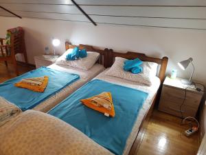 two beds in a room with blue sheets and towels at Nena & Rale Rooms in Donji Milanovac