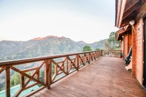 a wooden balcony with a view of the mountains at Avaas - Bed & Breakfast in Nainital
