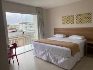 a bedroom with a bed and a large window at Hotel QualitySul in Teixeira de Freitas