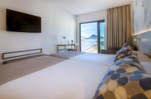 a hotel room with two beds and a large window at Hotel Cap Negret in Altea