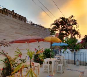 un patio con mesas, sombrillas y palmeras en Casa de Mainha Friendly Hostel, en Salvador