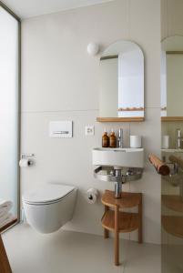 a white bathroom with a toilet and a sink at Carina - Design&Lifestyle hotel in Zermatt