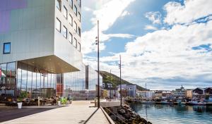 a building next to a body of water with boats at Smarthotel Hammerfest in Hammerfest