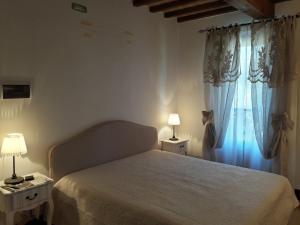 ein Schlafzimmer mit einem Bett und zwei Tischen mit Lampen in der Unterkunft Casa Lisa al Borgo in Ripalvella