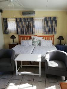 a bedroom with a large bed with two chairs at A Wave from it all in Port Shepstone