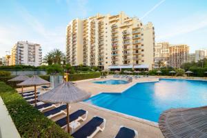 a swimming pool with chairs and umbrellas and a building at RR Club Amarilis in Portimão