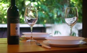 a table with two wine glasses and a bottle of wine at Chalés Maritacas in Maresias +21 photos