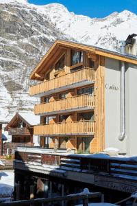 a wooden building with a snow covered mountain in the background at Carina - Design&Lifestyle hotel in Zermatt