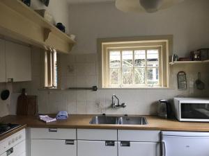 a kitchen with a sink and a microwave at De Sloep in Bergen