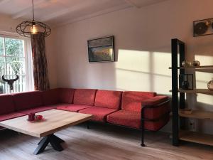a living room with a red couch and a table at De Specht in Bergen