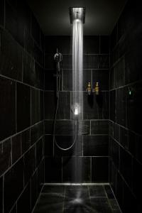 a black bathroom with a shower with a shower head at Carina - Design&Lifestyle hotel in Zermatt