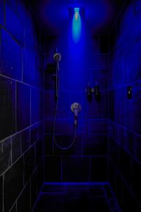 a bathroom with a blue light in a dark room at Carina - Design&Lifestyle hotel in Zermatt