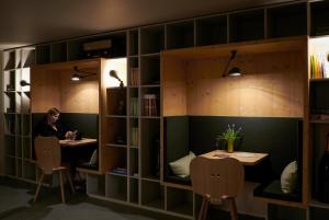 a person sitting at two tables in a library at Carina - Design&Lifestyle hotel in Zermatt