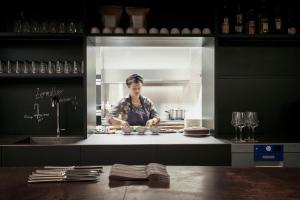a woman standing in a kitchen preparing food at Carina - Design&Lifestyle hotel in Zermatt