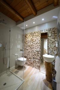 a bathroom with a stone wall and a sink and a shower at Hotel Vecchia Stazione Mountain Elegance in Roana